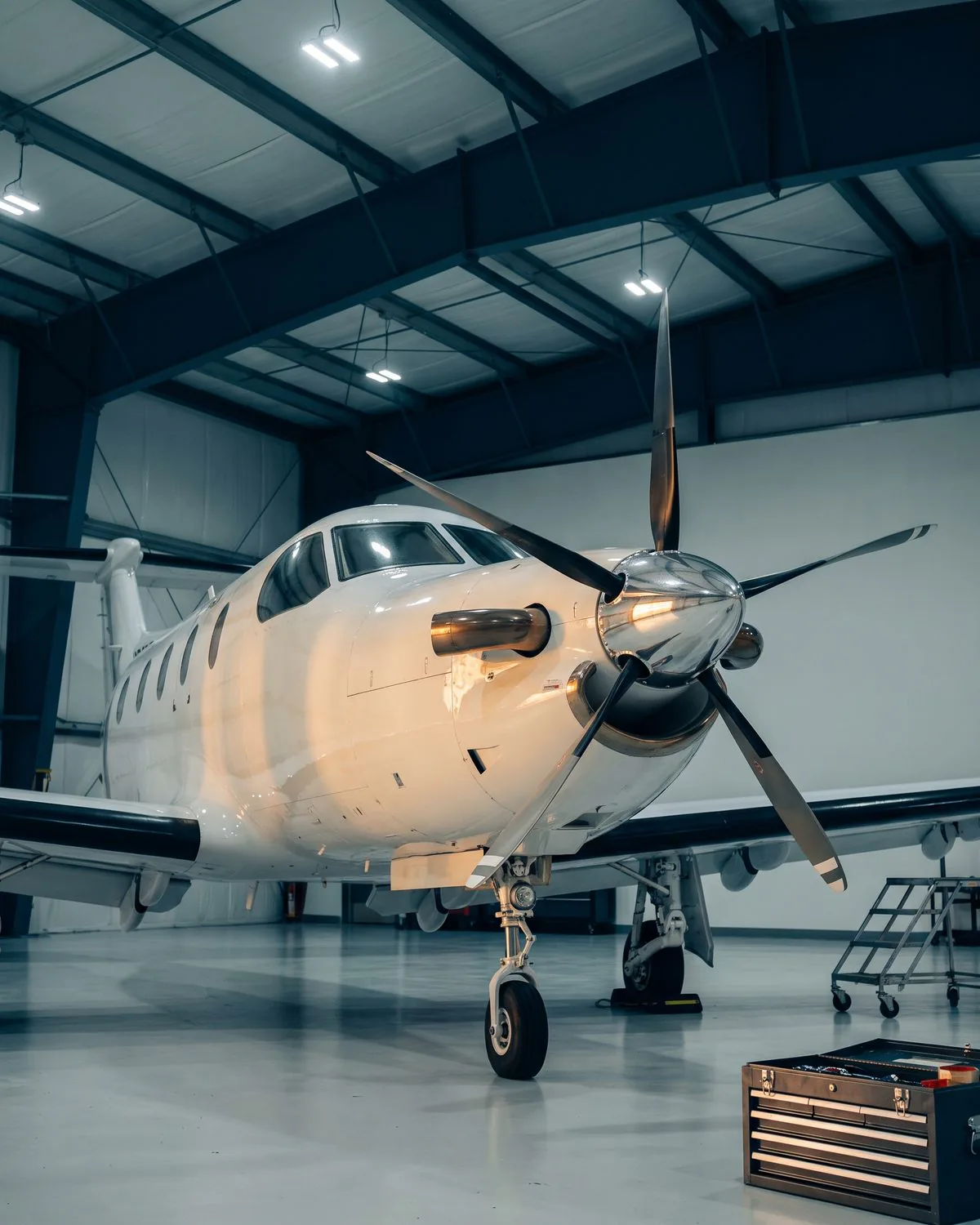 Single-engine turboprop in a private hangar under maintenance lighting